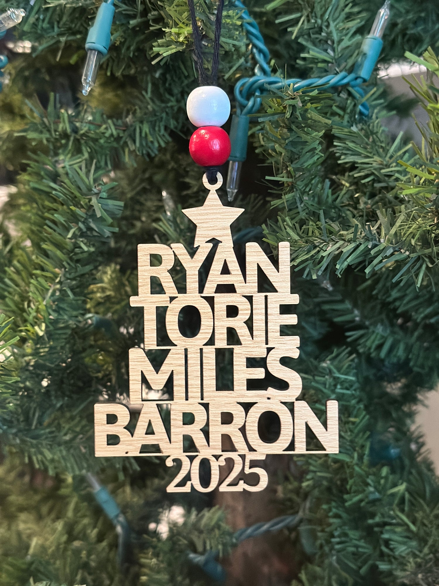 Personalized family Christmas ornament made of laser cut plywood in the shape of a Christmas Tree. Feature 4 family members' names with the shortest name on the top of the tree and the longest name on the bottom of the tree.